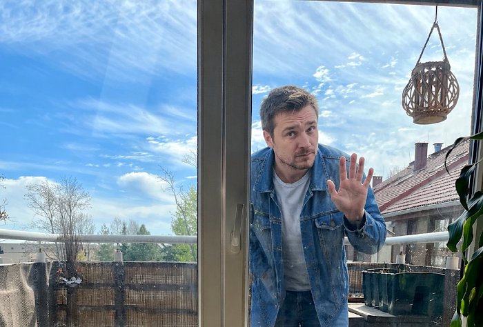 A photograph of a phone seller standing on a balcony and staring at the household members